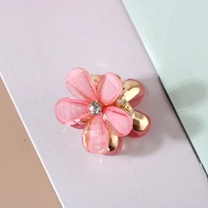 Close-up of pink resin flower hair claw clip with golden base and center sparkling rhinestone