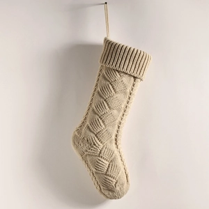 Close-up of beige chunky knit Christmas stocking with detailed cable stitch pattern