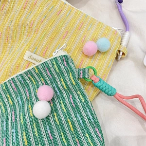 Detail of colorful knitted crossbody bags with fluffy pom-poms and adjustable straps