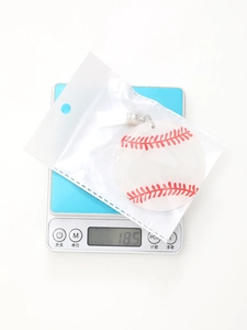 Detailed view of a baseball pattern keychain with white tassel on an electronic scale