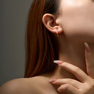 Close-up of a model wearing a small gold S925 sterling silver hoop earring with zircon
