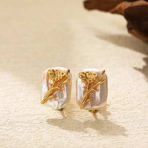 Detailed close-up of golden floral motifs on baroque pearl earrings with vintage texture