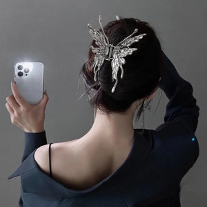Silver butterfly hair claw clip with fluid metal design on model's hairstyle