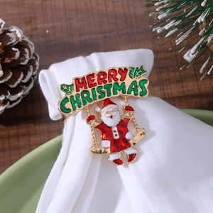 Golden Santa Claus napkin ring with Merry Christmas banner on white napkin and green plate