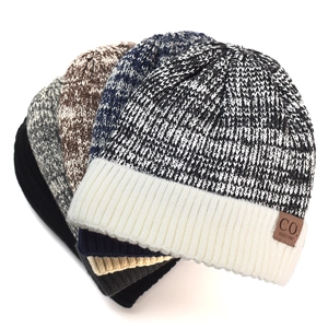 Close-up of assorted thick knitted winter beanies with soft fleece lining and leather tags