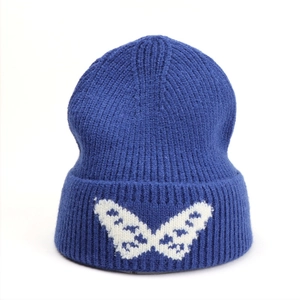 Detail of navy blue ribbed knit beanie featuring a white jacquard butterfly on the cuff