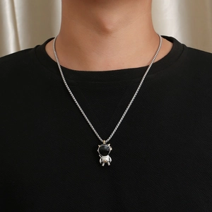 Macro shot of a titanium steel astronaut pendant necklace on a black crewneck shirt