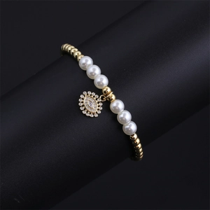 Detail of gold beads and white pearls bracelet with a sparkling Evil Eye charm