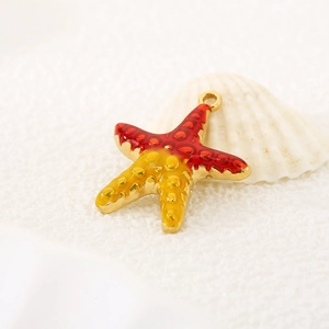 Macro shot of a red and yellow enamel starfish pendant with gold base and ocean details