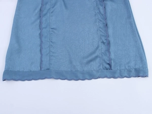 Détail de l'ourlet de robe bleue avec texture froissée et bords ondulés à coutures violettes