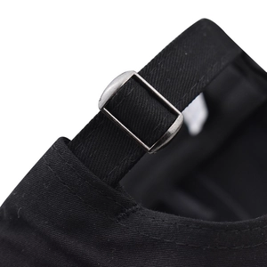 Détail de la boucle métallique et de la texture du tissu sergé sur la casquette en coton noir