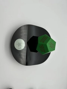 Close-up of green 12-sided gift exchange dice on scale weighing 36.7 grams for party games