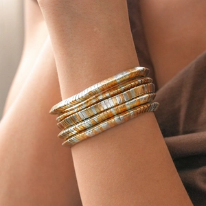 Detail of two-tone gold and silver interlocking metallic geometric bangle on wrist