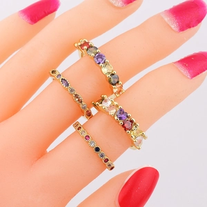 Juego de cuatro anillos dorados con circonitas multicolores en los dedos de la modelo