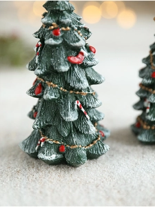 Macro detail of a green resin Christmas tree with snow coating and festive ornaments