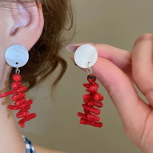 Detail view of retro red resin earrings with white circular accents on a model