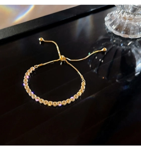 Macro shot of a gold tennis bracelet with cubic zirconia and adjustable bolo clasp design