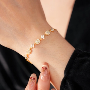 Close-up of gold-plated square and flower link bracelet with white zircon on a wrist
