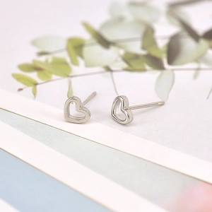 Minimalist S925 sterling silver hollow heart stud earrings on eucalyptus leaf background