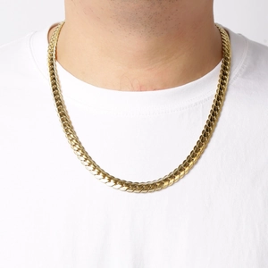Close-up of a golden Cuban link chain necklace worn on neck over a white t-shirt