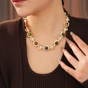 Gros plan d'un collier vintage avec perles blanches et pierres vertes sur un mannequin