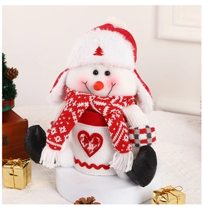 Cute snowman plush gift bag on a decorative pedestal with festive Christmas ornaments