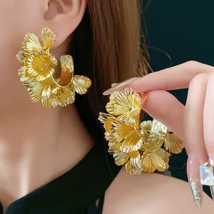 Exaggerated gold floral hoop earrings with textured petal design worn by a model
