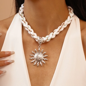 Metallic sun pendant on white twisted rope necklace worn by a fashion model