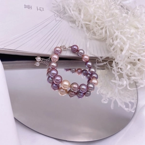 Detail of colorful Baroque Edison pearls bracelet with adjustable silver clasp on a book