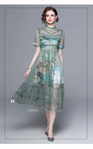 Detailed close-up of green embroidered tulle dress with floral patterns and short sleeves