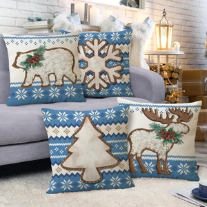 Close-up of four Christmas linen pillowcases with polar bear and elk prints on a sofa
