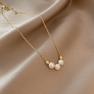 French retro gold necklace featuring three white pearls and gold beads on silk background