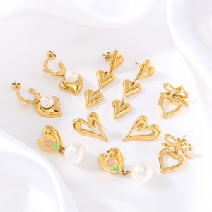Golden heart and bow earrings set with pearls on white silk, stainless steel jewelry