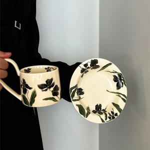 Vintage iris ceramic coffee cup and saucer set with cream glaze and hand-held view