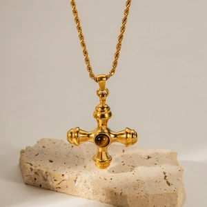Macro detail of 18K gold stainless steel cross pendant with round tiger eye stone inlay
