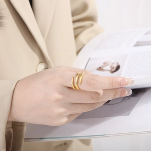 Close-up of a minimalist gold multi-layer wrap ring worn by a model in a beige suit