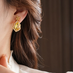 Close-up of vintage gold teardrop earring featuring a yellow gem and fine diamond pavé