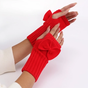 Close-up of red knitted fingerless gloves with bow decoration and soft wool texture