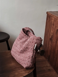 Dettaglio macro della trama in tessuto tweed rosa e manico intrecciato della borsa