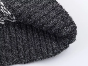 Macro shot of dark grey ribbed knit texture with soft wool fibers and white pattern detail
