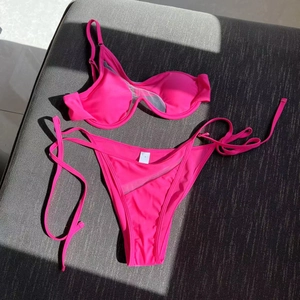 Detail of hot pink cutout bikini featuring asymmetric mesh stitching and side ties