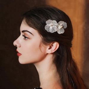 Paire de peignes à fleurs blanches avec perles sur cheveux châtain foncé