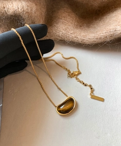 Detailed close-up of 18k gold plated pea-shaped tiger eye stone pendant on chain