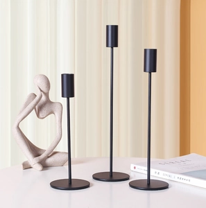 Set of three matte black metal pillar candle holders with stepped heights and slim rods