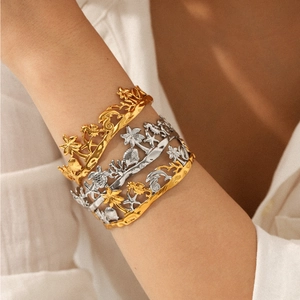 Three oceanic stainless steel bangles featuring coconut trees and sea life on model wrist
