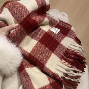 Close-up of red and white plaid scarf featuring soft tassels and a woven brand label