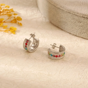 Macro shot of silver C-shaped earrings with colorful gemstones and twisted texture detail