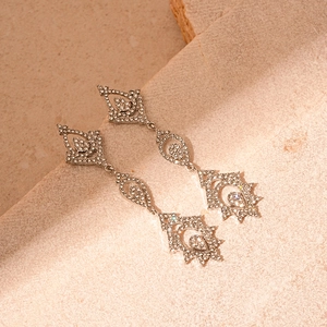 Boucles d'oreilles pendantes de luxe argentées avec strass sur une surface en pierre
