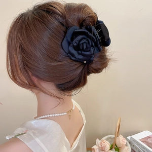 Dettaglio elegante molletta per capelli con rosa in raso nero per acconciatura francese