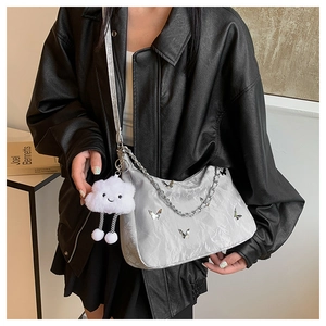 Detail of silver metallic crossbody bag with butterfly ornament and white plush charm